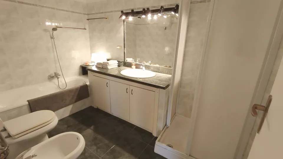 Bad mit Waschtisch, Spiegel, Dusche, Badewanne und Bidet.