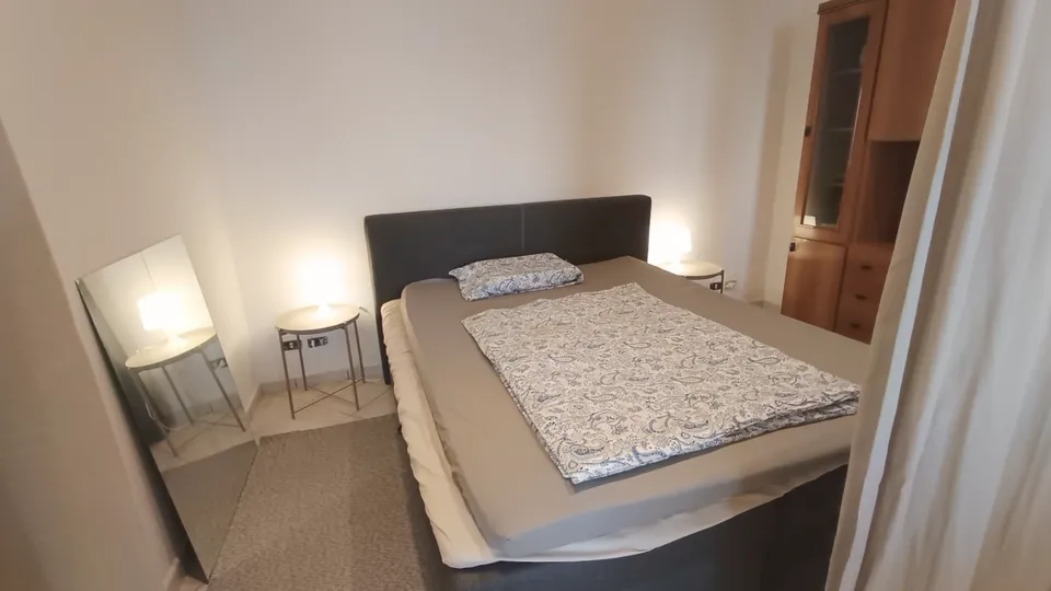 Schlafzimmer mit Doppelbett, gemusterter Tagesdecke und zwei Nachttischlampen.